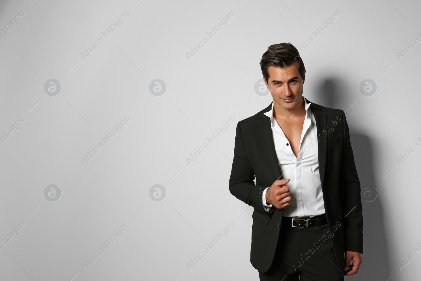 Photo of Handsome young man in elegant suit on light beige background. Space for text