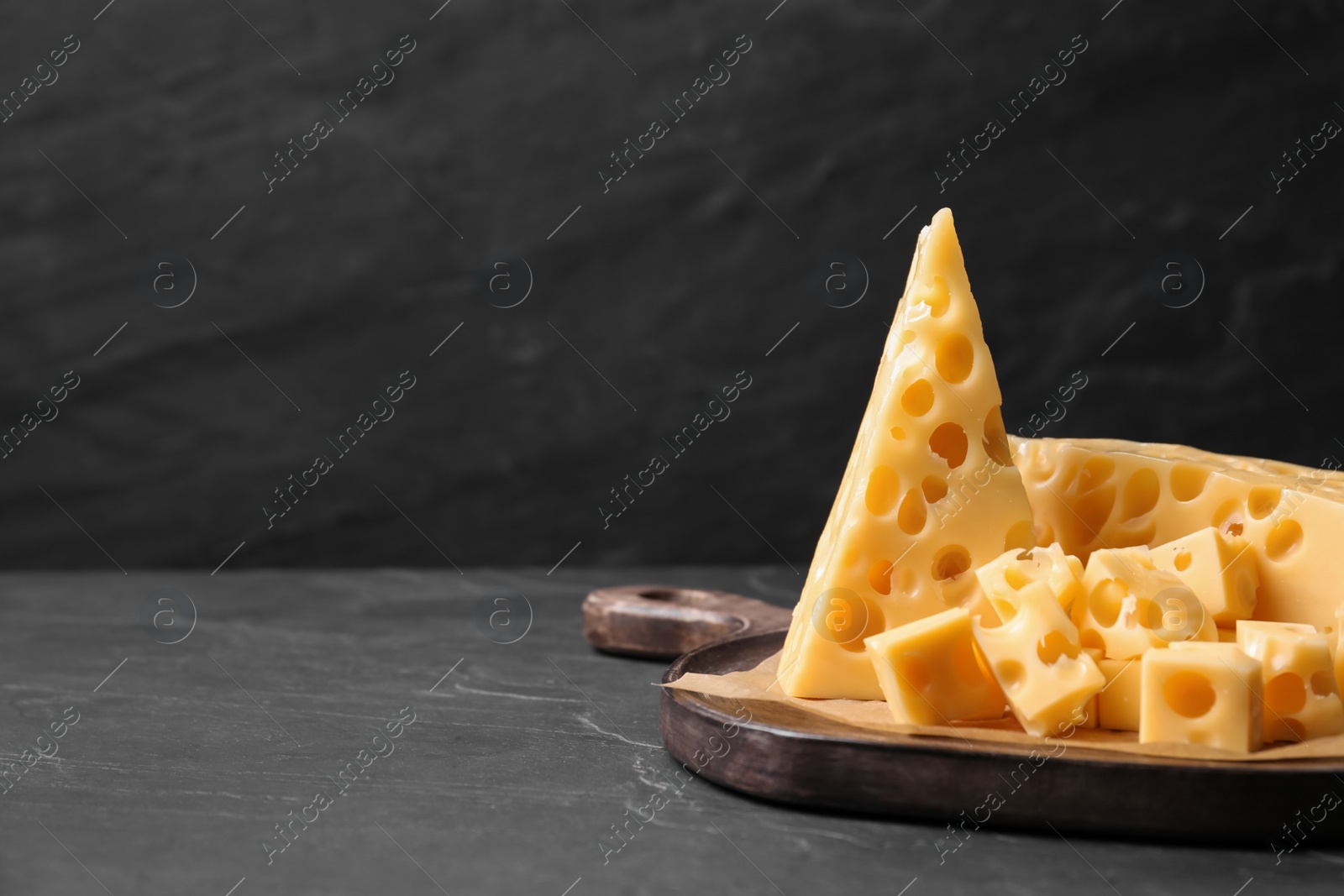 Photo of Tasty fresh cheese on dark grey table, closeup. Space for text