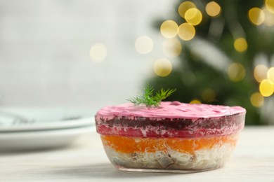 Herring under fur coat salad on white wooden table against blurred festive lights, space for text. Traditional Russian dish