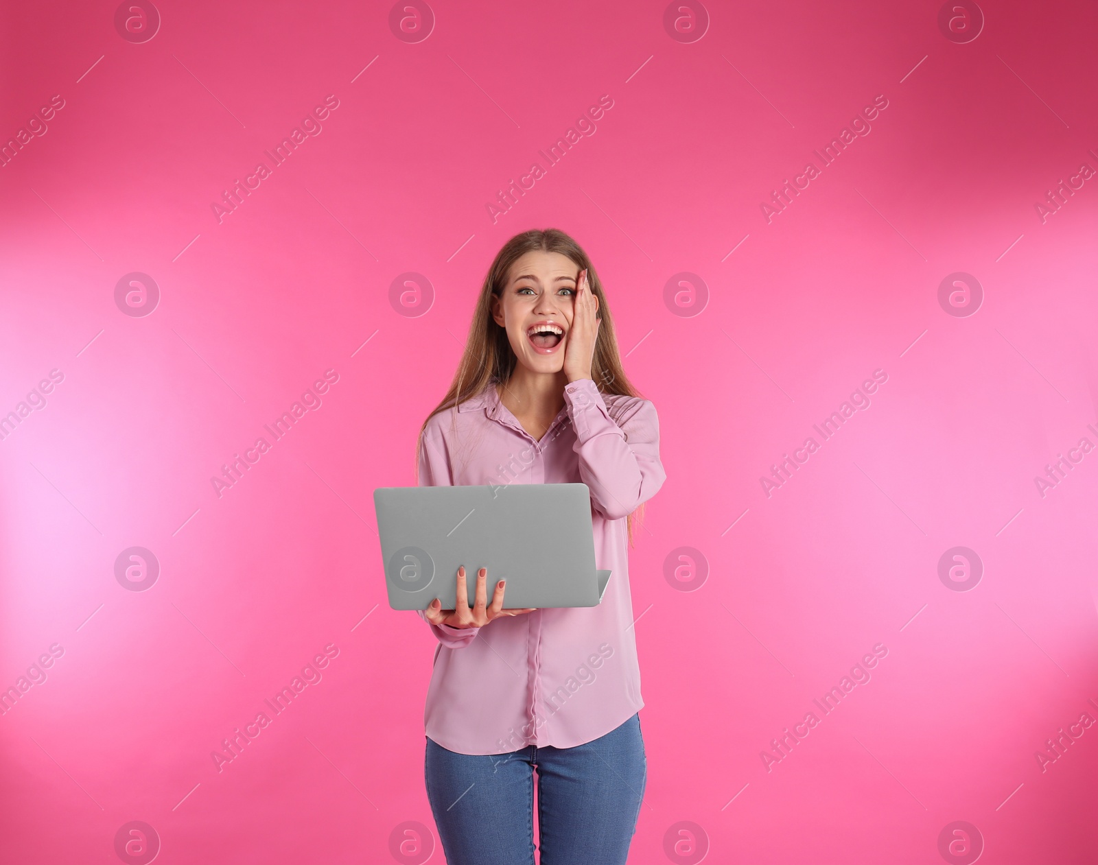 Photo of Emotional young woman with laptop celebrating victory on color background