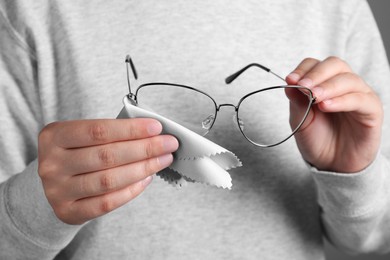 Photo of Woman cleaning glasses with microfiber cloth, closeup