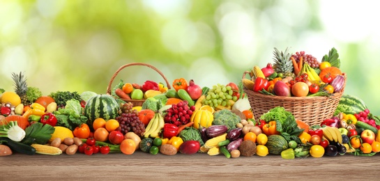 Image of Assortment of fresh organic vegetables and fruits on wooden table against blurred green background. Banner design 