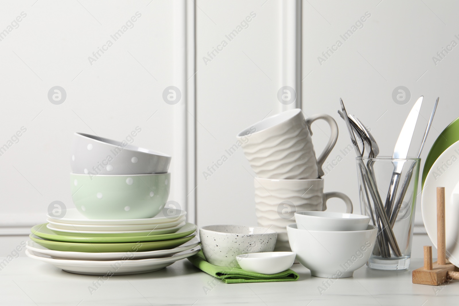 Photo of Beautiful ceramic dishware, cups and cutlery on white marble table