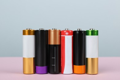 Image of Many new AA batteries on color background