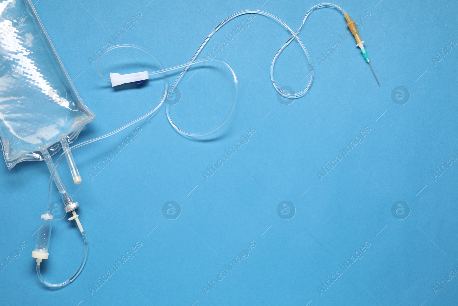 Photo of IV infusion set on light blue background, top view. Space for text