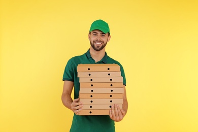 Photo of Young courier with pizza boxes on color background. Food delivery service