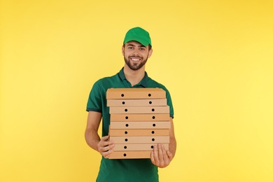 Young courier with pizza boxes on color background. Food delivery service