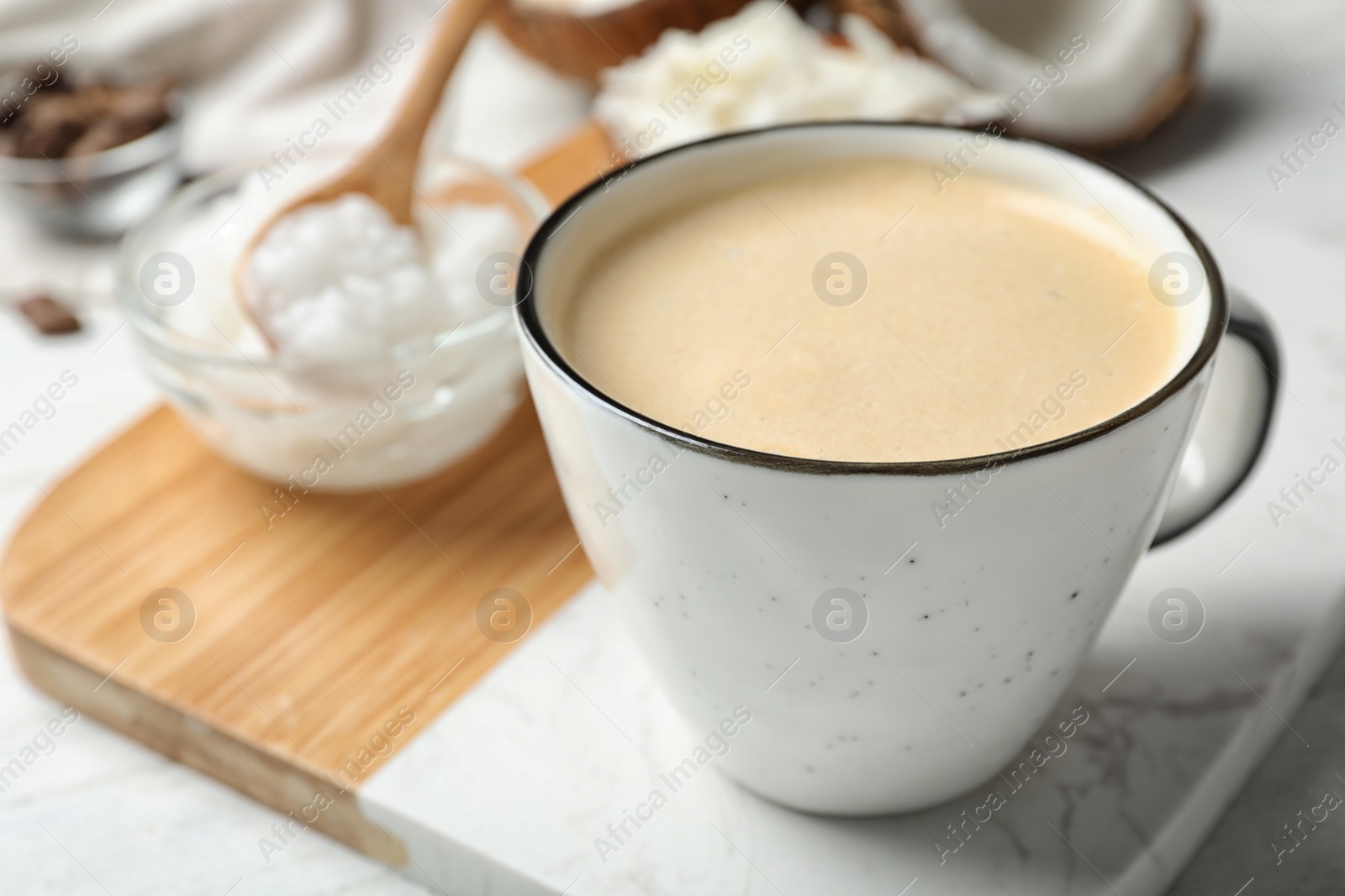 Photo of Delicious coffee with organic coconut oil on white wooden table