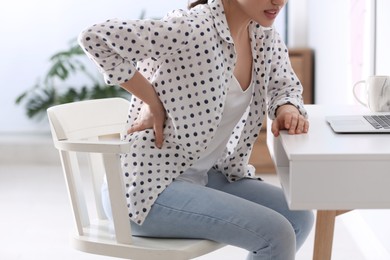 Woman suffering from back pain in office, closeup. Bad posture problem