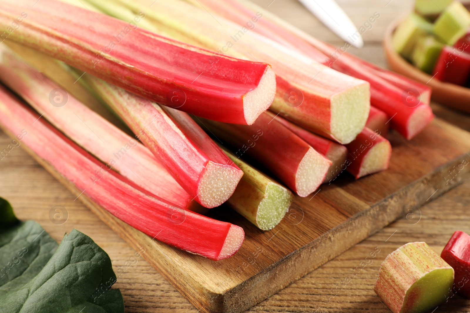 Photo of Many cut rhubarb stalks on wooden table, closeup