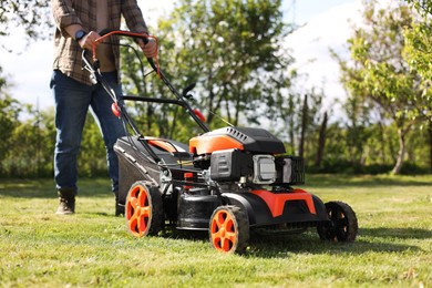 Man cutting green grass with lawn mower in garden, selective focus