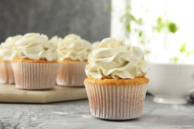 Photo of Tasty cupcakes with vanilla cream on grey table, closeup