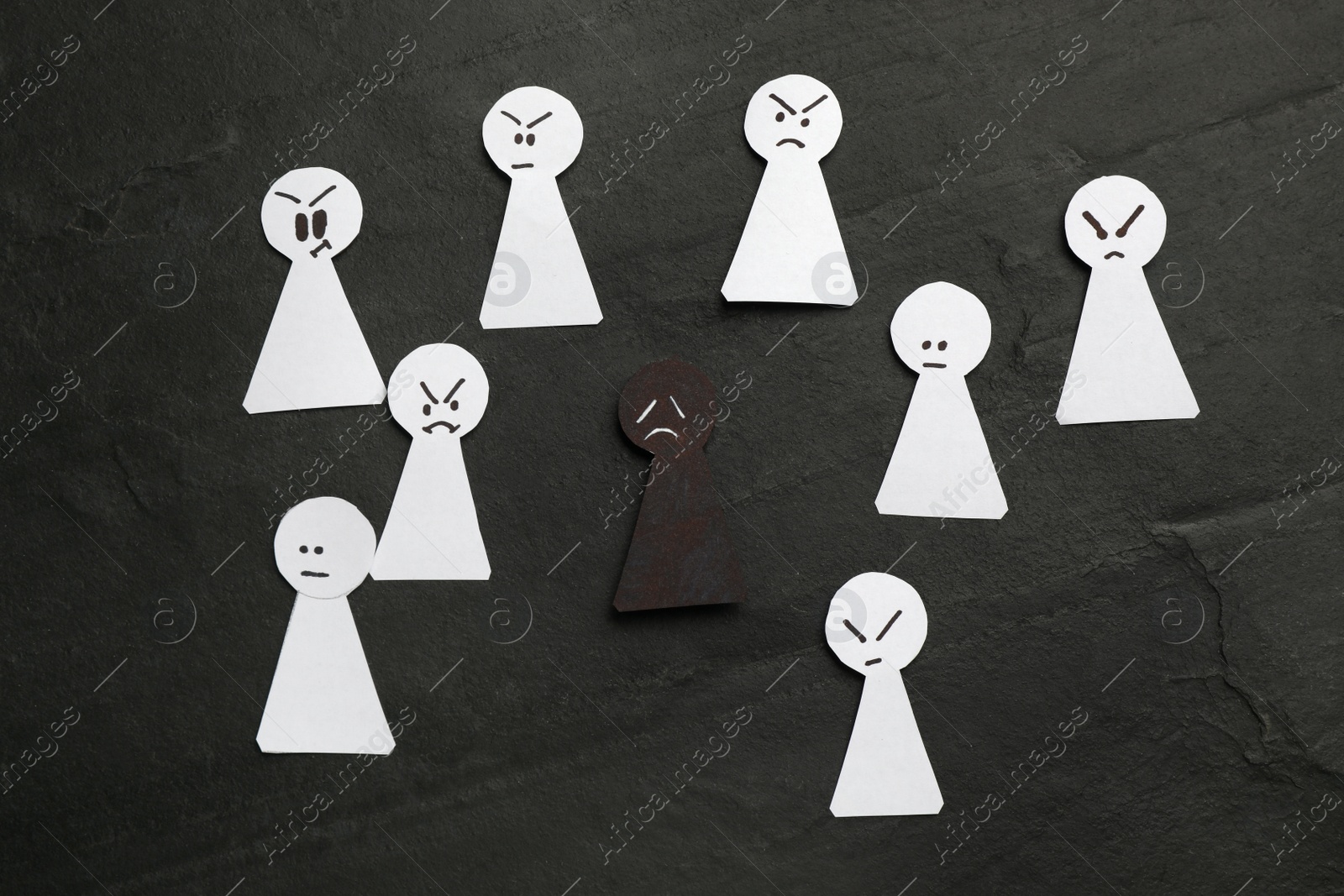 Photo of Black paper figure among white ones on dark background, flat lay. Racism concept