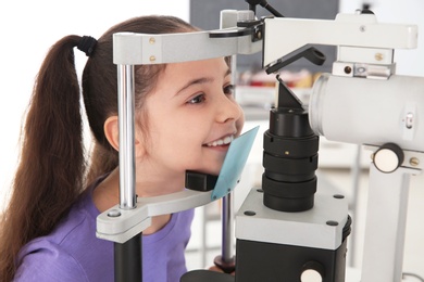 Photo of Little girl visiting children's doctor in clinic. Eye examination