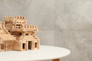 Photo of Wooden castle on white table, space for text. Children's toy