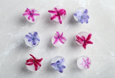 Photo of Ice cubes with flowers on grey background, flat lay