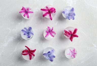 Ice cubes with flowers on grey background, flat lay