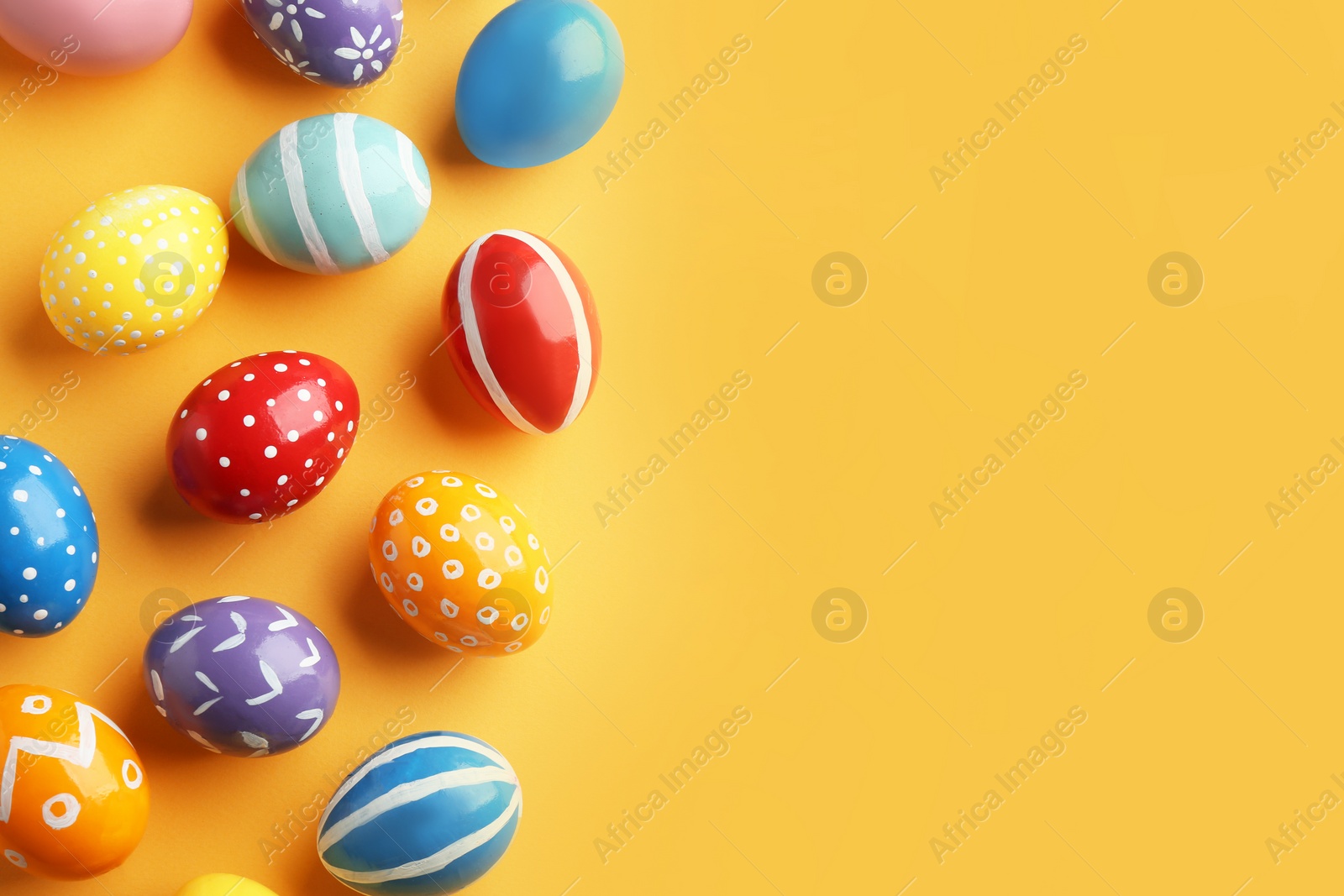 Photo of Flat lay composition of painted Easter eggs on color background, space for text