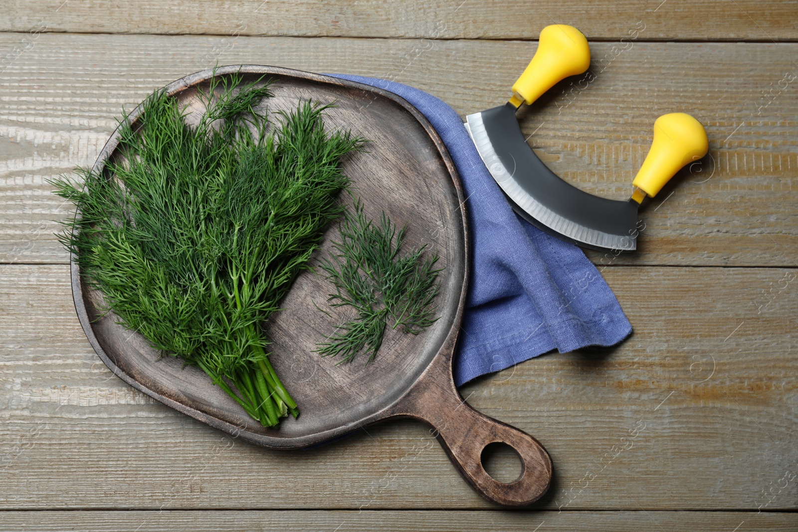 Photo of Bunch of fresh dill and mincing knife on wooden table, flat lay