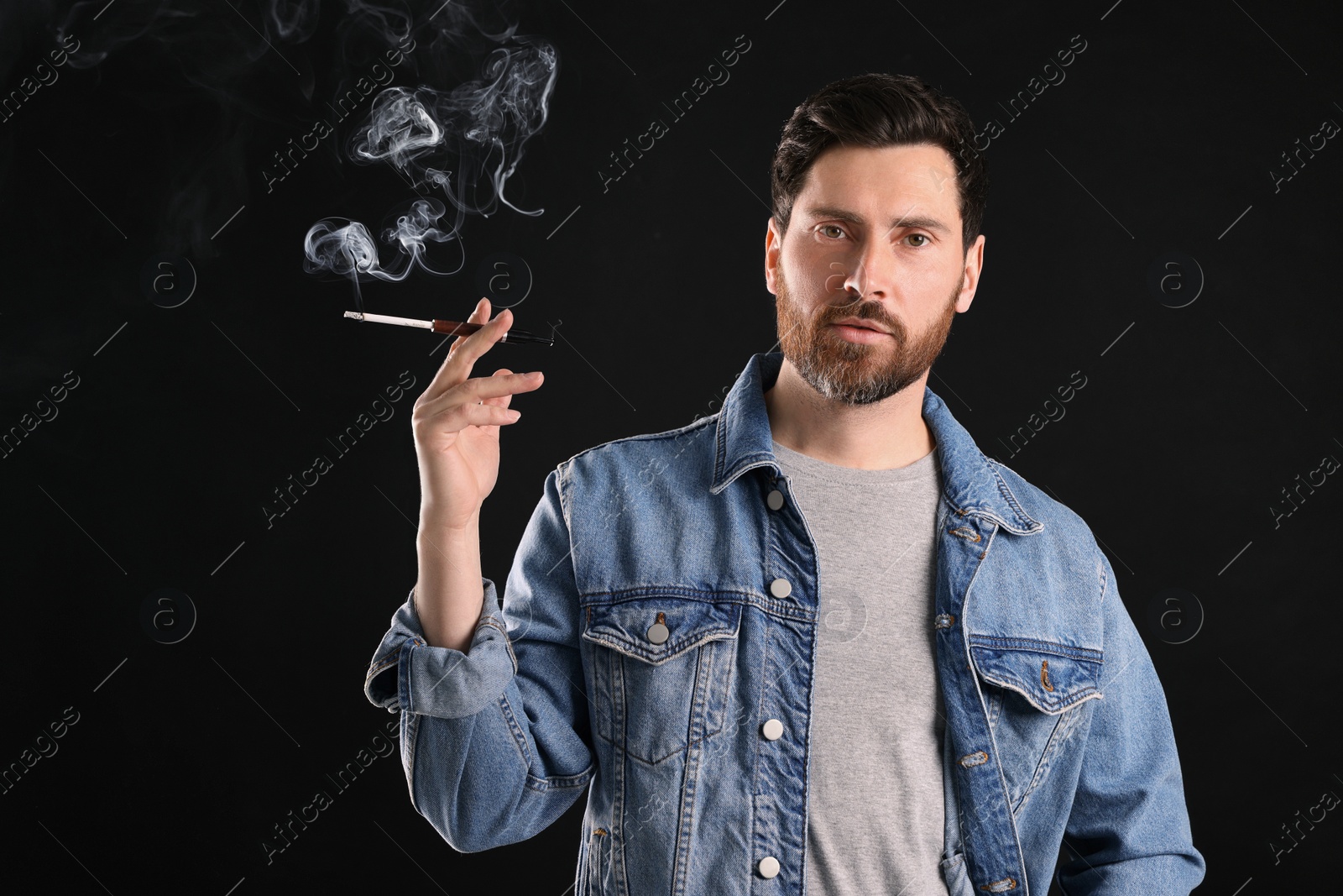 Photo of Man using cigarette holder for smoking on black background, space for text