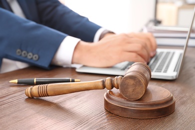 Photo of Gavel and blurred lawyer working with laptop on background