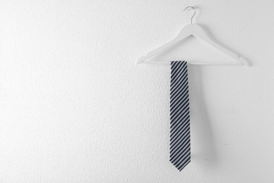 Tie on wooden hanger against white background. Space for text