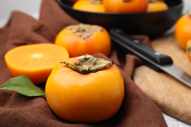 Photo of Whole and cut delicious ripe persimmons on table, closeup