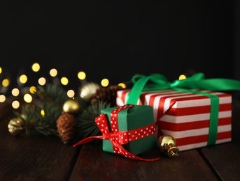 Photo of Christmas gift boxes with fir tree branches on wooden table. Space for text