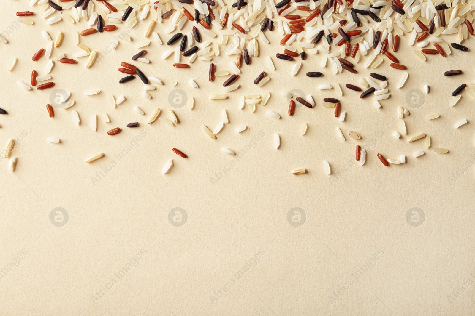 Photo of Mixed brown and other types of rice on color background, top view with space for text