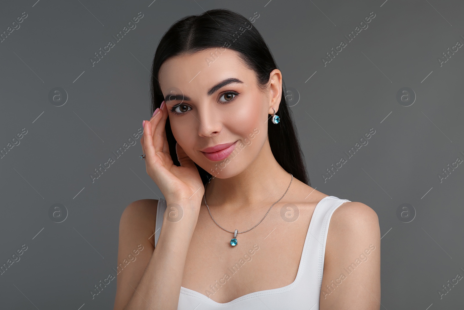 Photo of Beautiful young woman with elegant jewelry on dark grey background