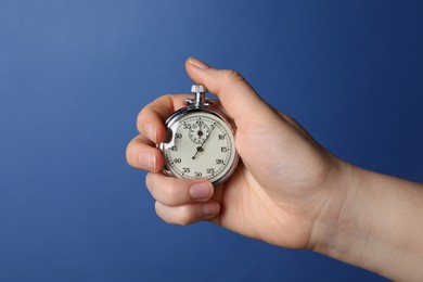 Photo of Woman holding vintage timer on blue background, closeup