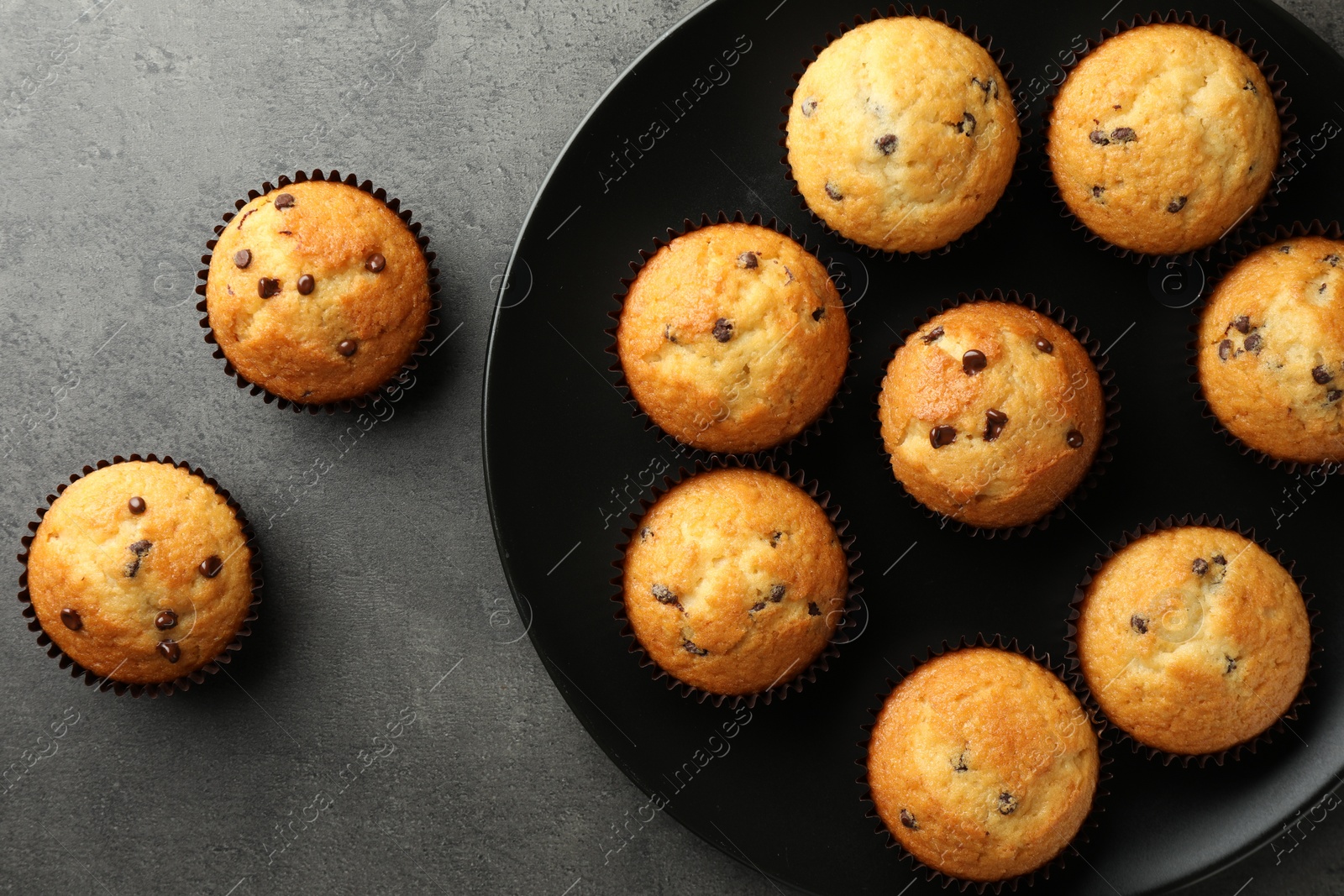 Photo of Delicious freshly baked muffins with chocolate chips on gray table, top view