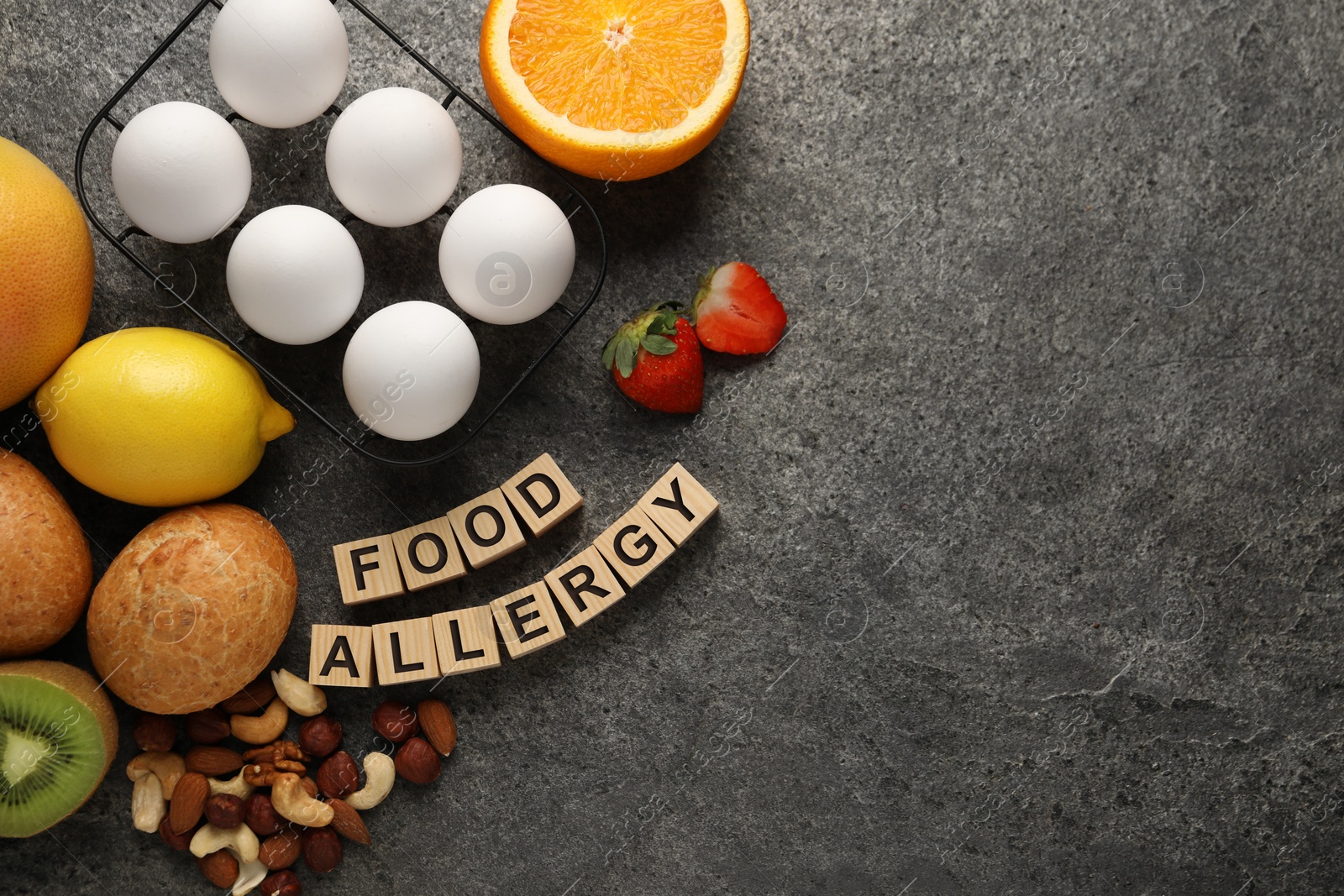 Image of Food allergy. Different fresh products and wooden cubes on grey table, flat lay with space for text