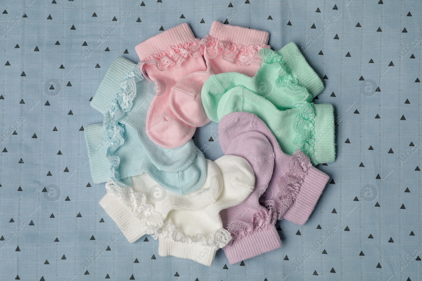 Photo of Many colorful baby socks on light blue fabric, flat lay