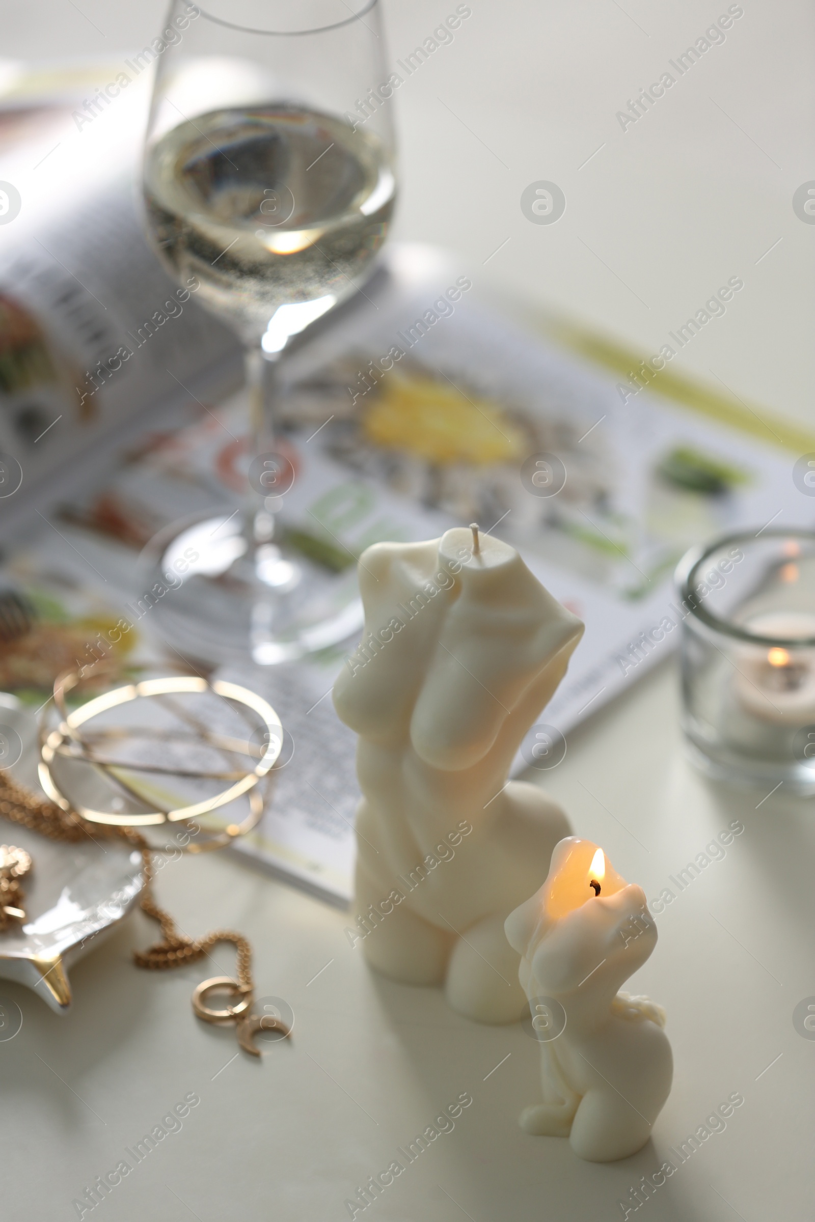Photo of Beautiful body shaped candles and jewelry on white table indoors