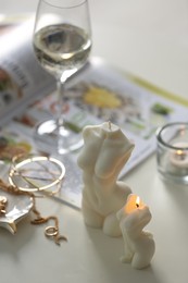 Photo of Beautiful body shaped candles and jewelry on white table indoors