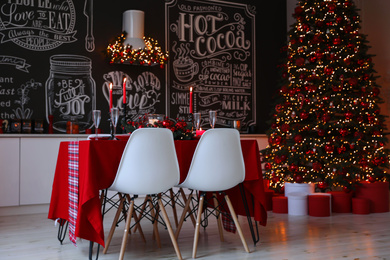 Photo of Stylish kitchen interior with festive table and decorated Christmas tree