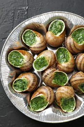 Photo of Delicious cooked snails on dark textured table, top view