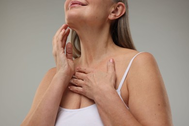 Woman with healthy skin on grey background, low angle view