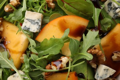 Photo of Tasty salad with persimmon, blue cheese and walnuts as background, top view