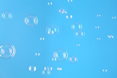 Beautiful transparent soap bubbles on light blue background