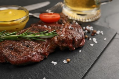 Delicious fried steak with rosemary and sauce on black table, closeup