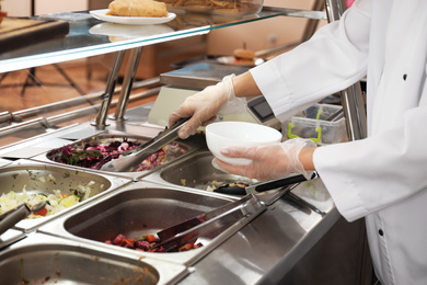 Photo of School canteen worker at serving line, closeup. Tasty food