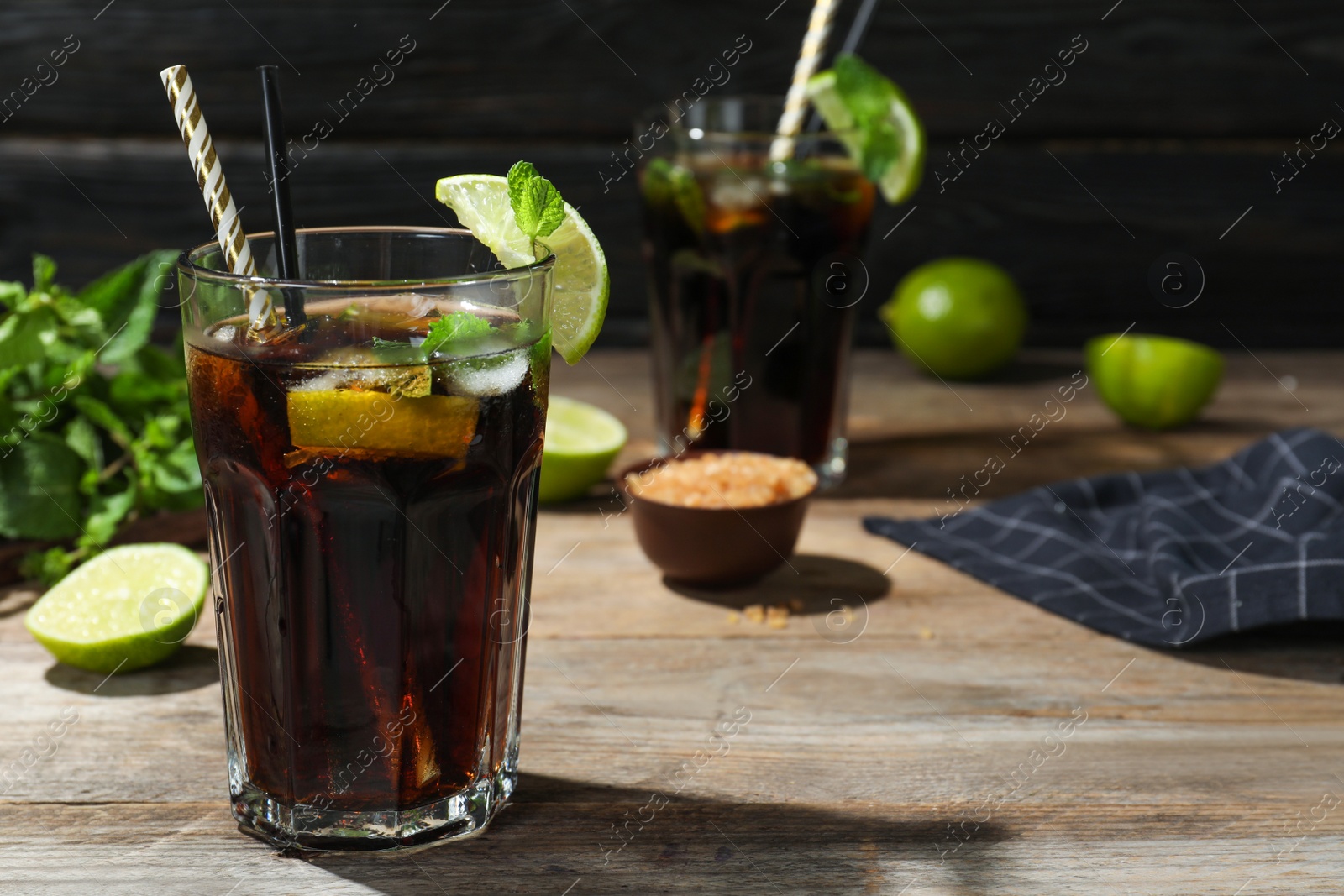 Photo of Glass of delicious cocktail with ice on table against dark wooden background. Space for text