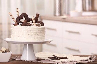 Delicious cake decorated with sweets on wooden table in kitchen, space for text