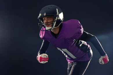 Photo of American football player in uniform running on dark background