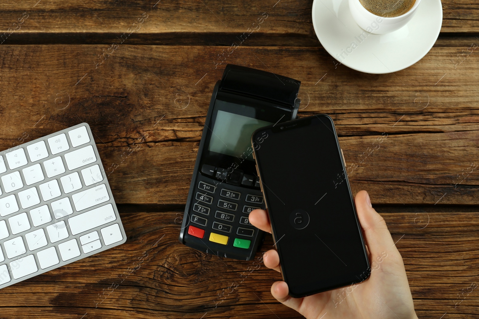 Photo of Woman with credit card using modern payment terminal at wooden table, top view