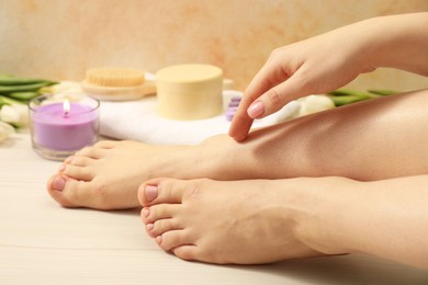 Photo of Woman with neat toenails after pedicure procedure on wooden floor, closeup