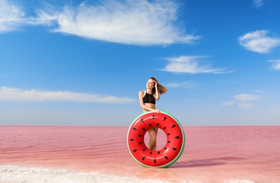 Photo of Beautiful woman with inflatable ring posing near pink lake on sunny day