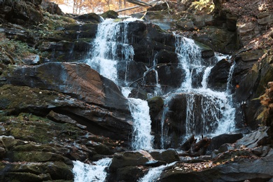 Photo of Beautiful waterfall with stones in park. Clear stream